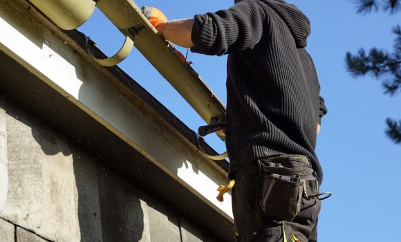 A low angle shot of a construction worker working and fixing a roof