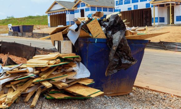 When house is being constructed, metal garbage container is used to dispose of construction waste